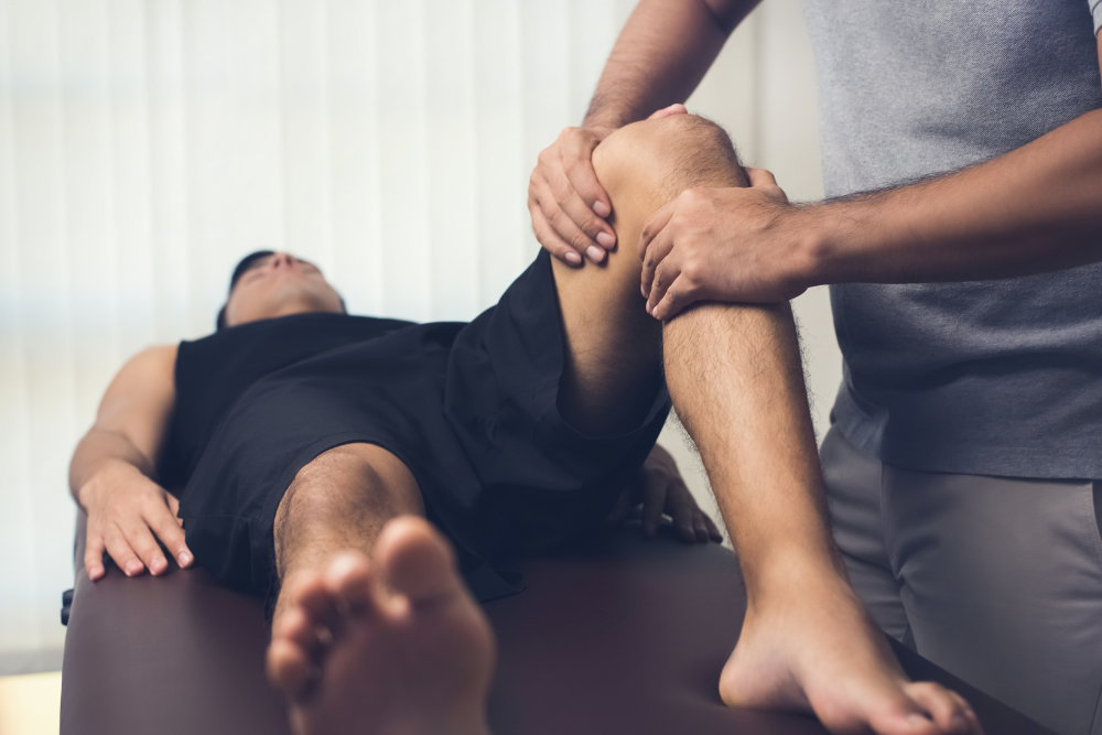 Physiotherapist treating athlete male patient af Atstock Productions fra Getty Images